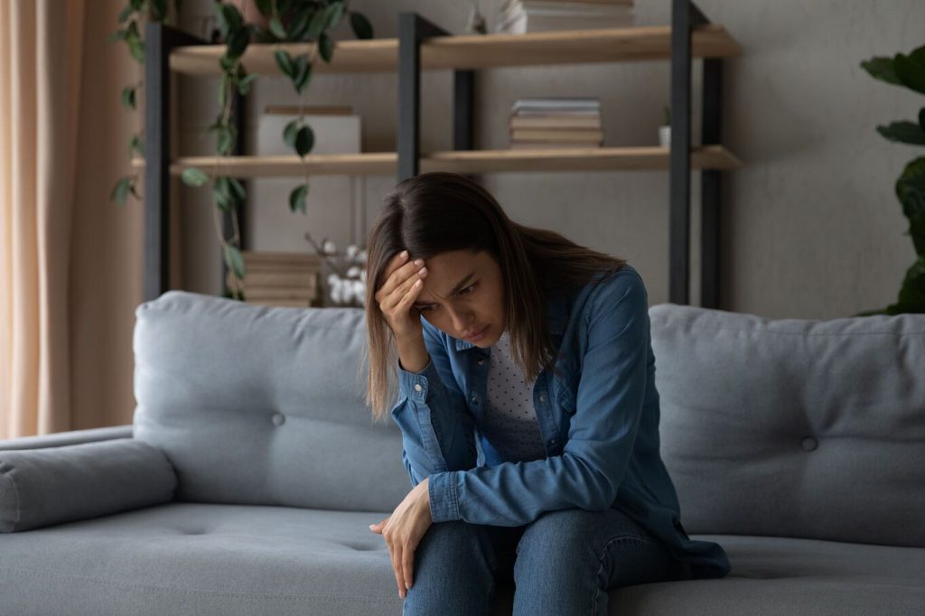 Managing Allegations, young woman sat alone looking distressed.