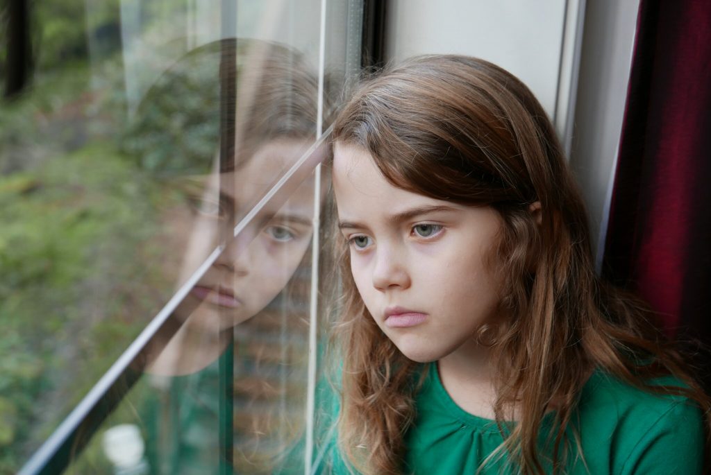 Understanding Attachment Development Trauma, young girl looking depressed starring out of a window