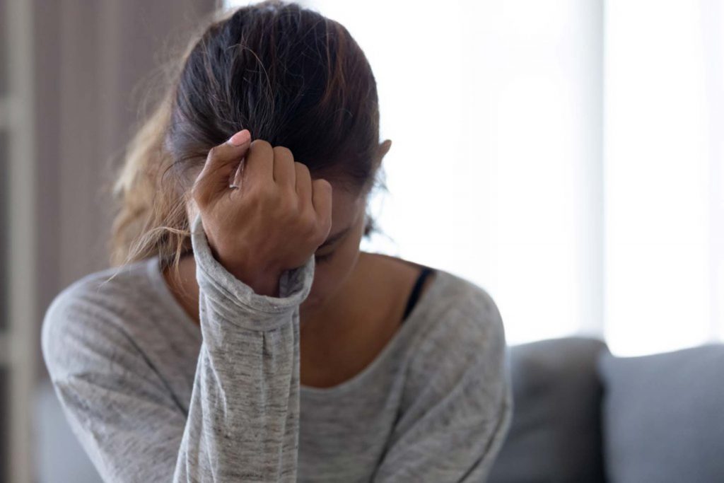 Understanding Depression Anxiety, adolescent looking depressed, holding head in hands.