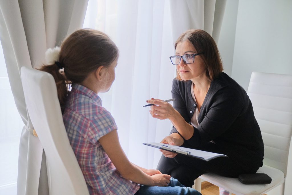 Woman social worker talking to girl child psychology mental health.