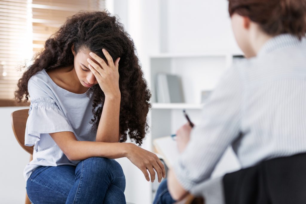 PTSD, young person looking distressed speaking to therapist/psychologist.