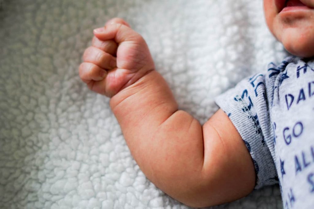 Paediatric First Aid, young baby in bed with arm out.