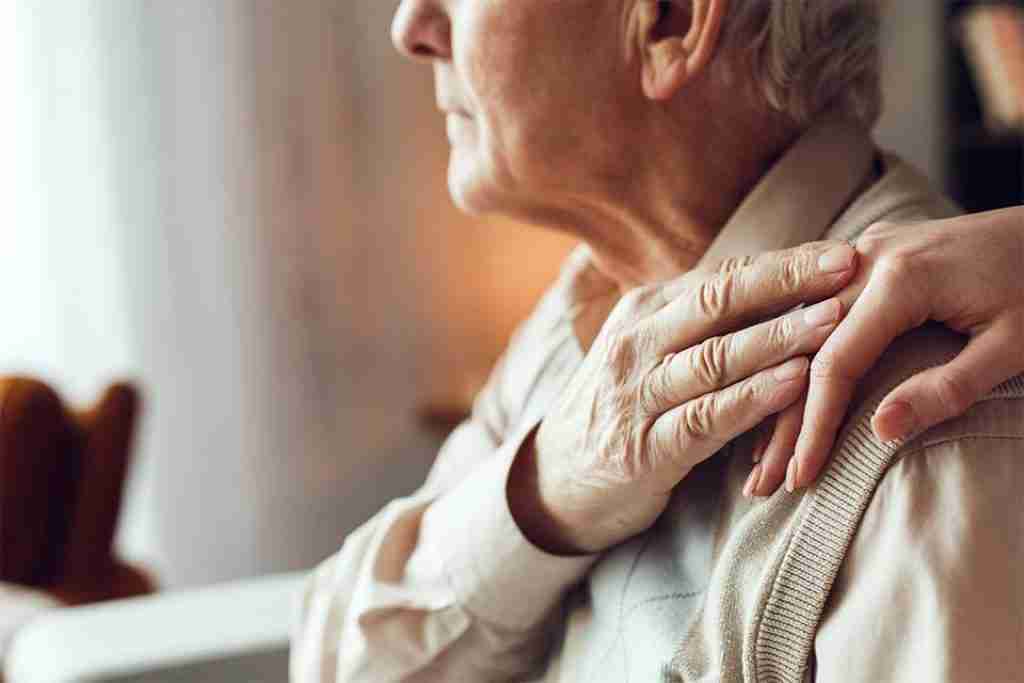 Advanced Dementia Care Training. An elderly gentleman with advanced dementia holding a hand on his shoulder reaching.