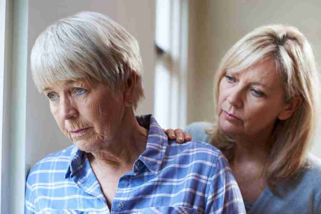 An elderly woman with dementia looking out of a window dementia behaviour changes.